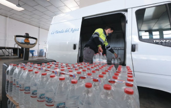 Personal cargando agua embotellada en la furgoneta